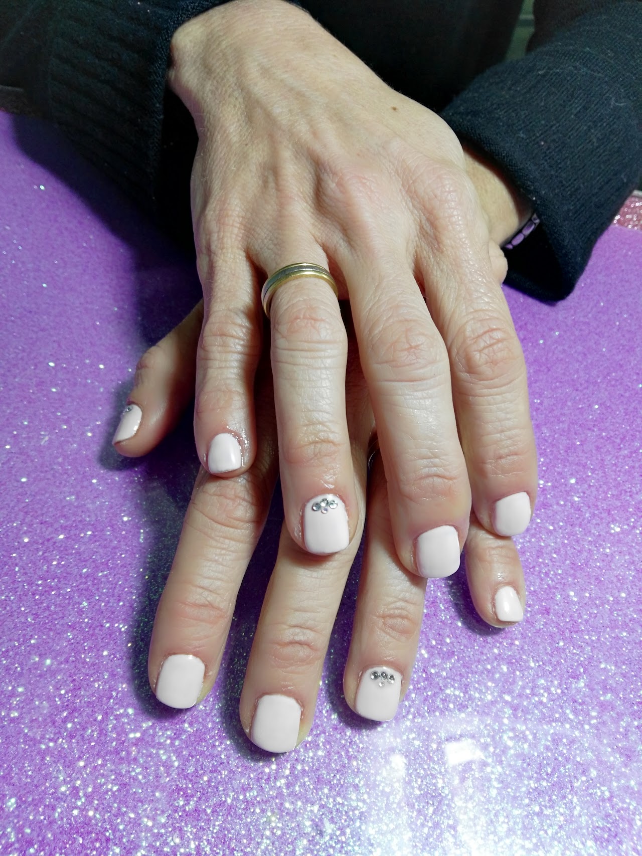 Close-up luxury shot of perfectly manicured feminine hands with elegant French manicure and soft rose pink and gold foil nail art accents, resting gracefully on a soft blush velvet textile, professional editorial beauty studio lighting, shallow depth of field, high-end salon aesthetic.