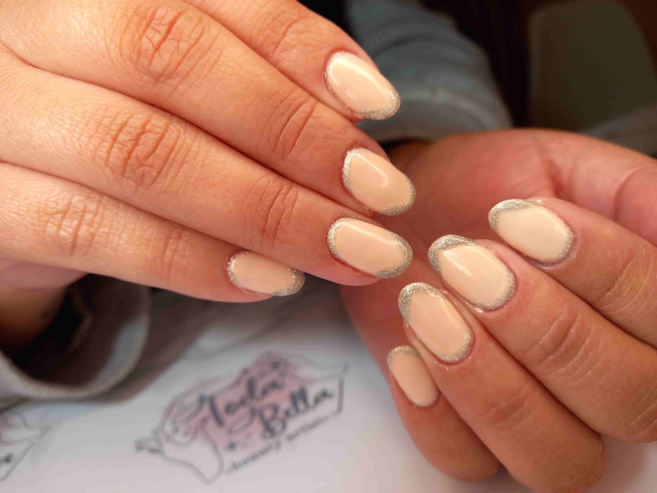 Close-up detail of manicured nails with delicate soft pink pastel gel polish and subtle champagne gold glitter line accents, clean natural aesthetic, soft daylight salon photography.